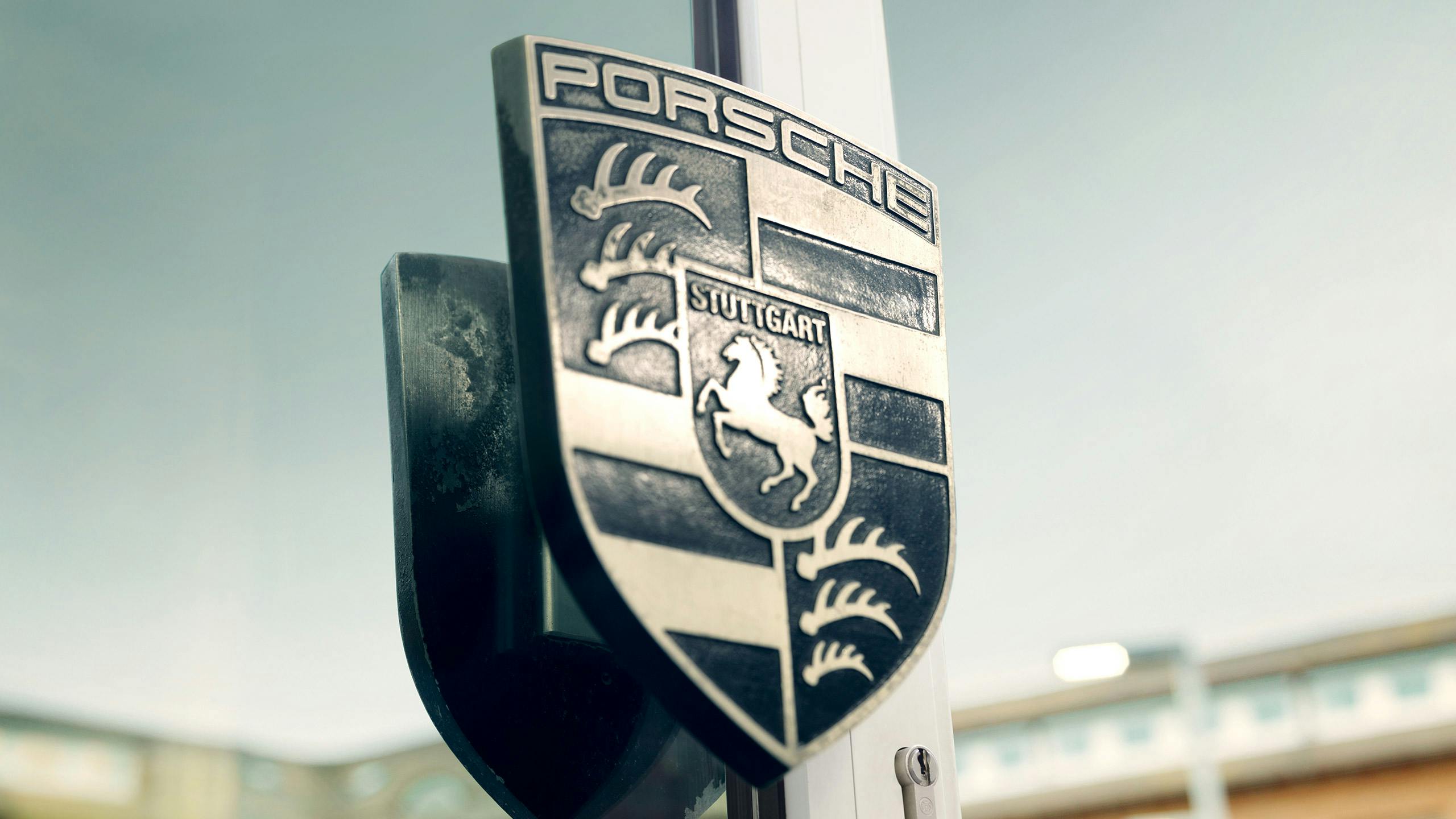 Das Porsche Logo als Türgriff im Eingangsbereich eines Porsche Standorts.
