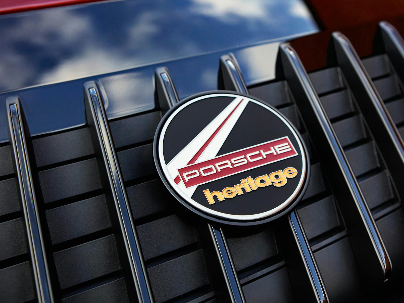 Detailed view of the Heritage Design badge on the rear lid grille of the Porsche 911 Targa 4S Heritage Design Edition in Cherry Metallic.
