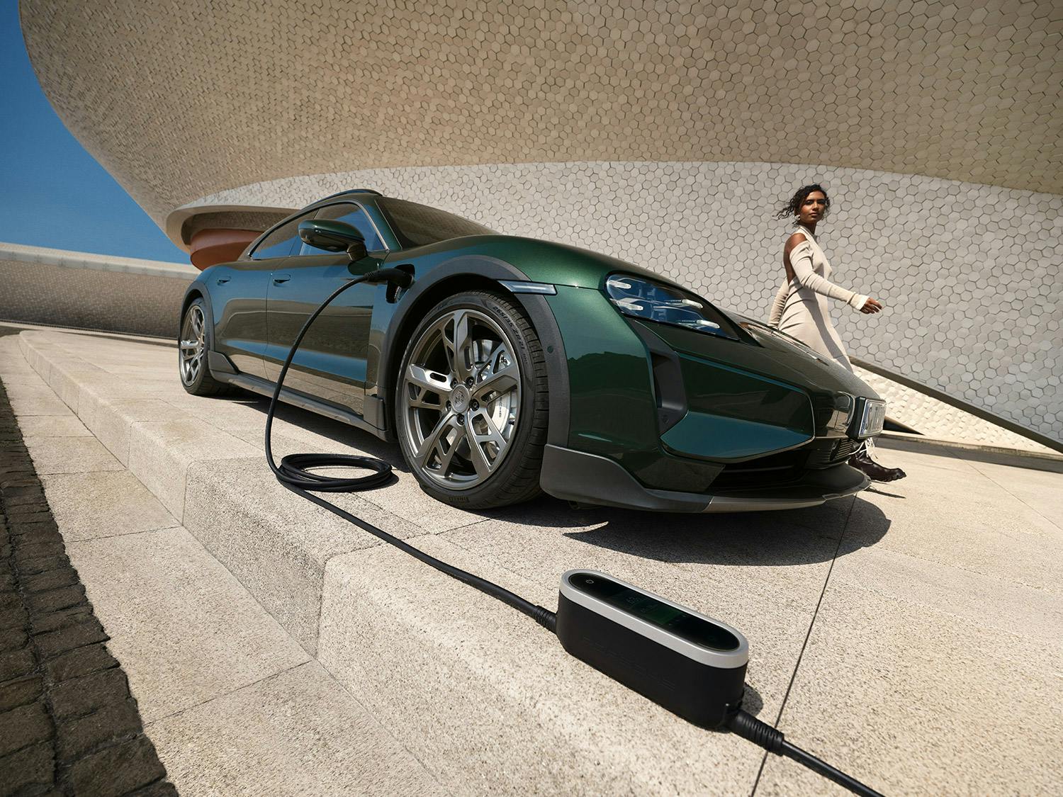 View of the front of a Porsche Taycan Turbo Cross Turismo next to a Wallbox.