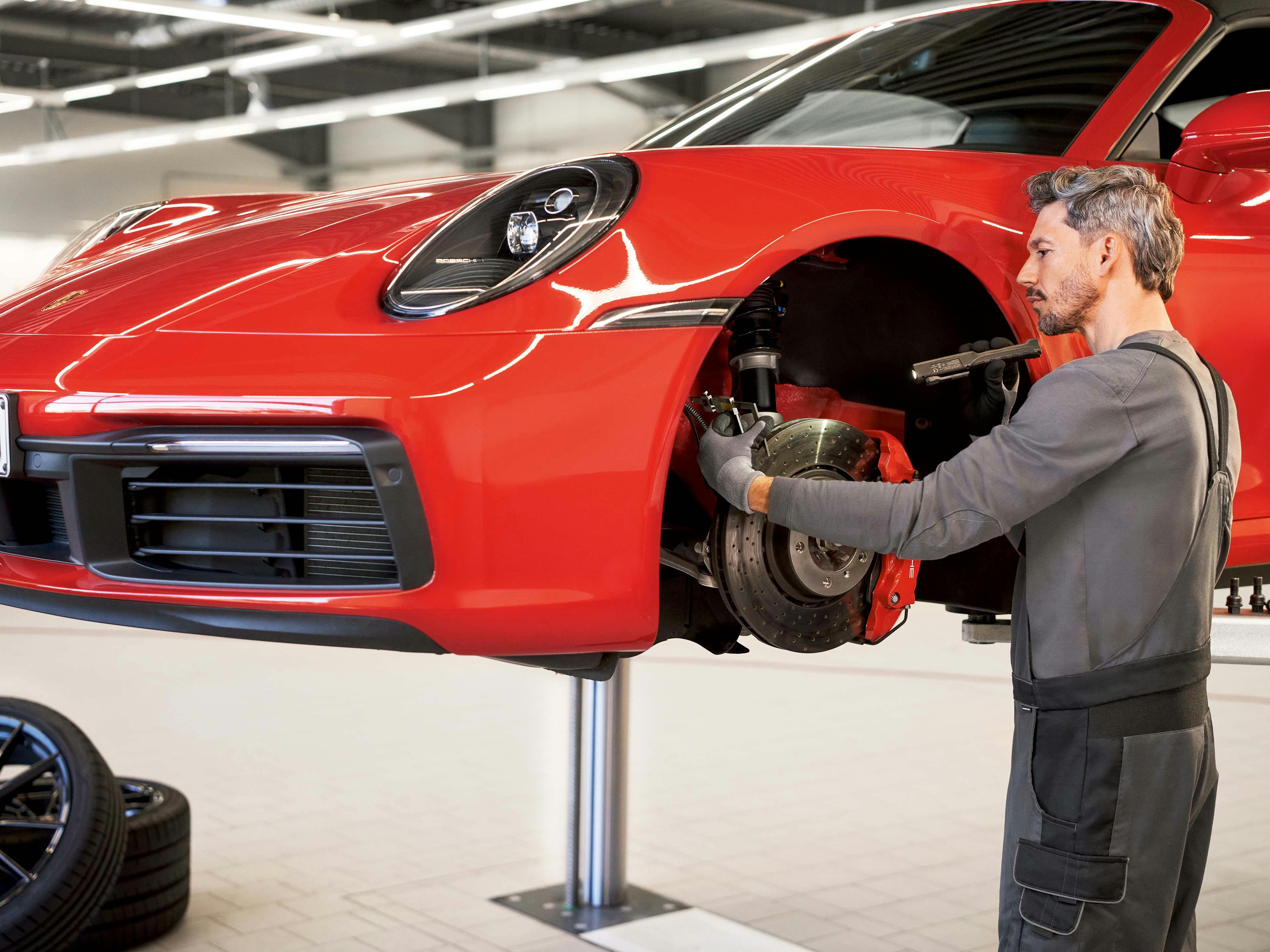 Een monteur checkt de remmen van een Porsche in de werkplaats