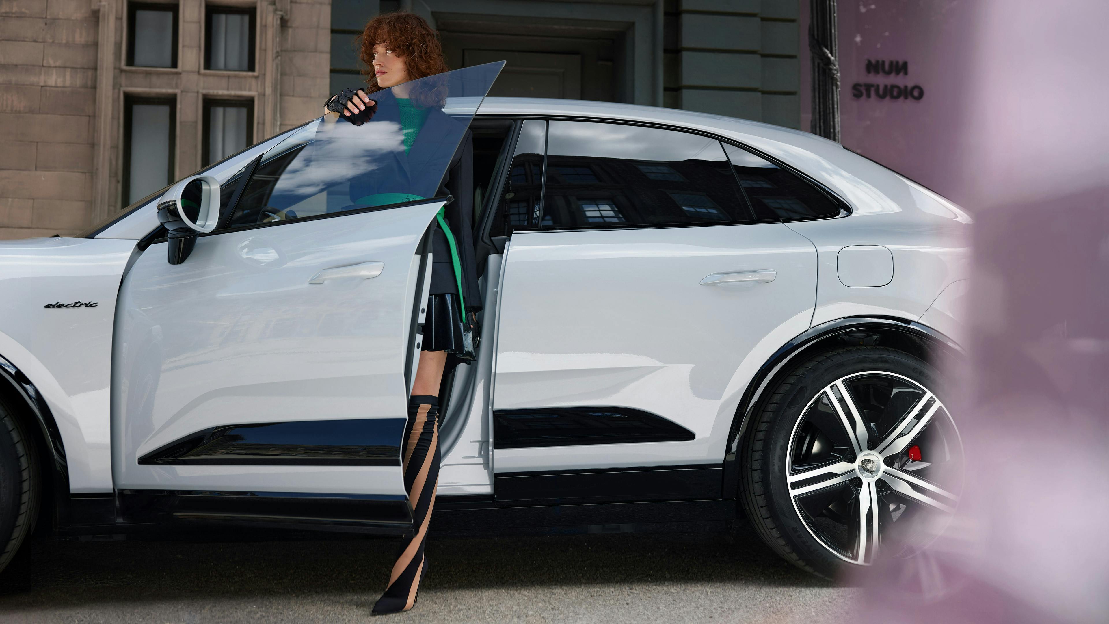Eine Frau steigt aus einem weißen Porsche Macan aus.