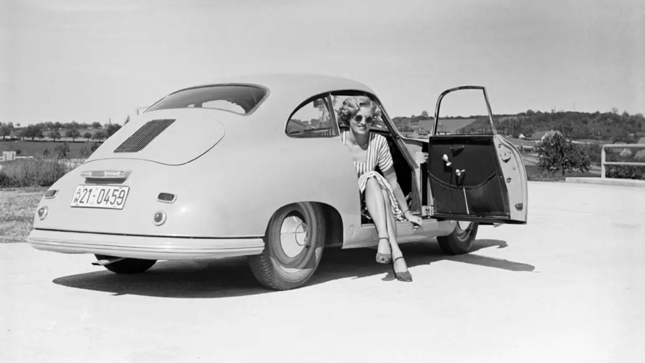 A woman sitting in a classic Porsche.