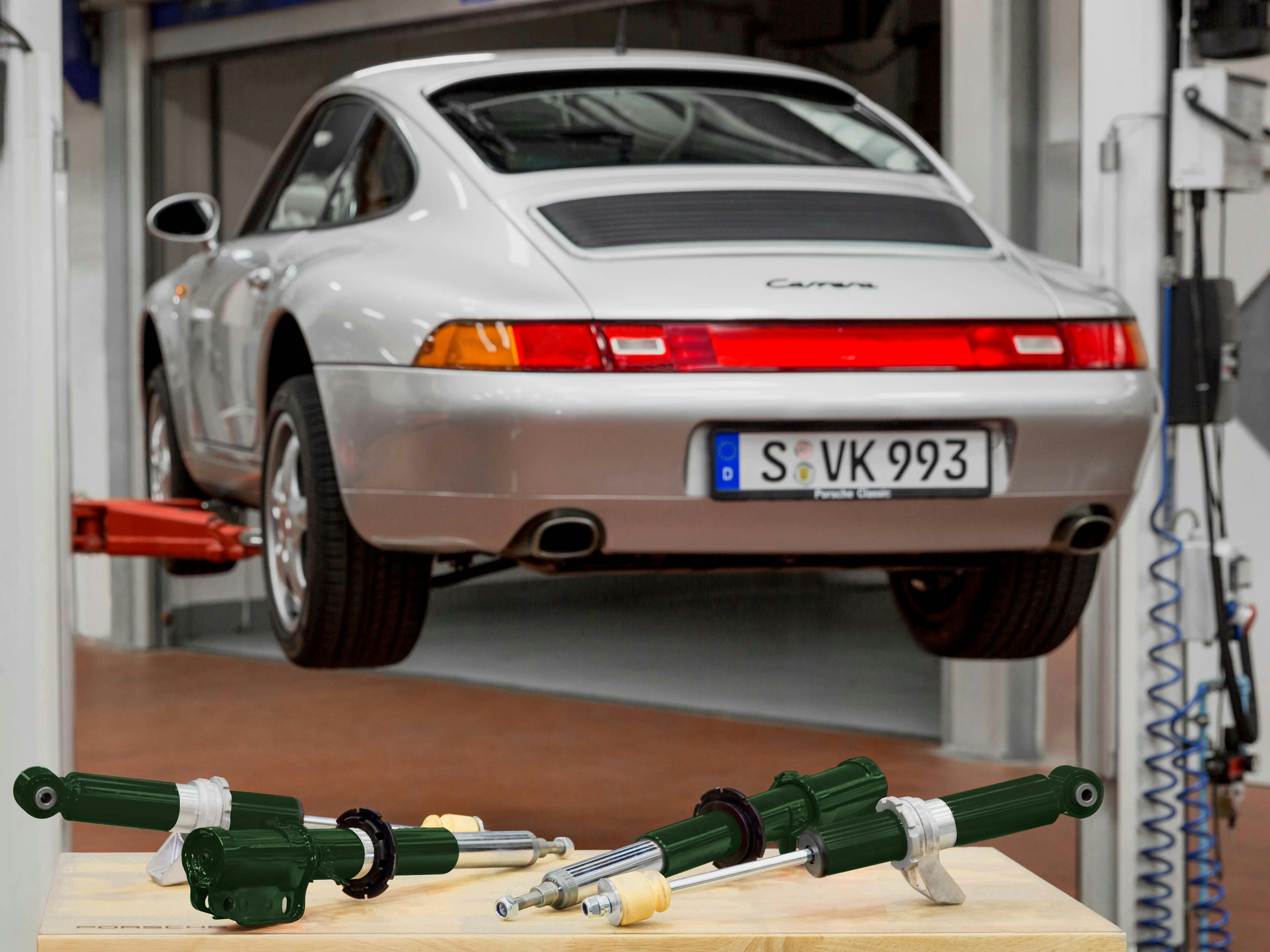 Detail shot: Green shock absorbers for the 993, a Porsche Carrera in the background.