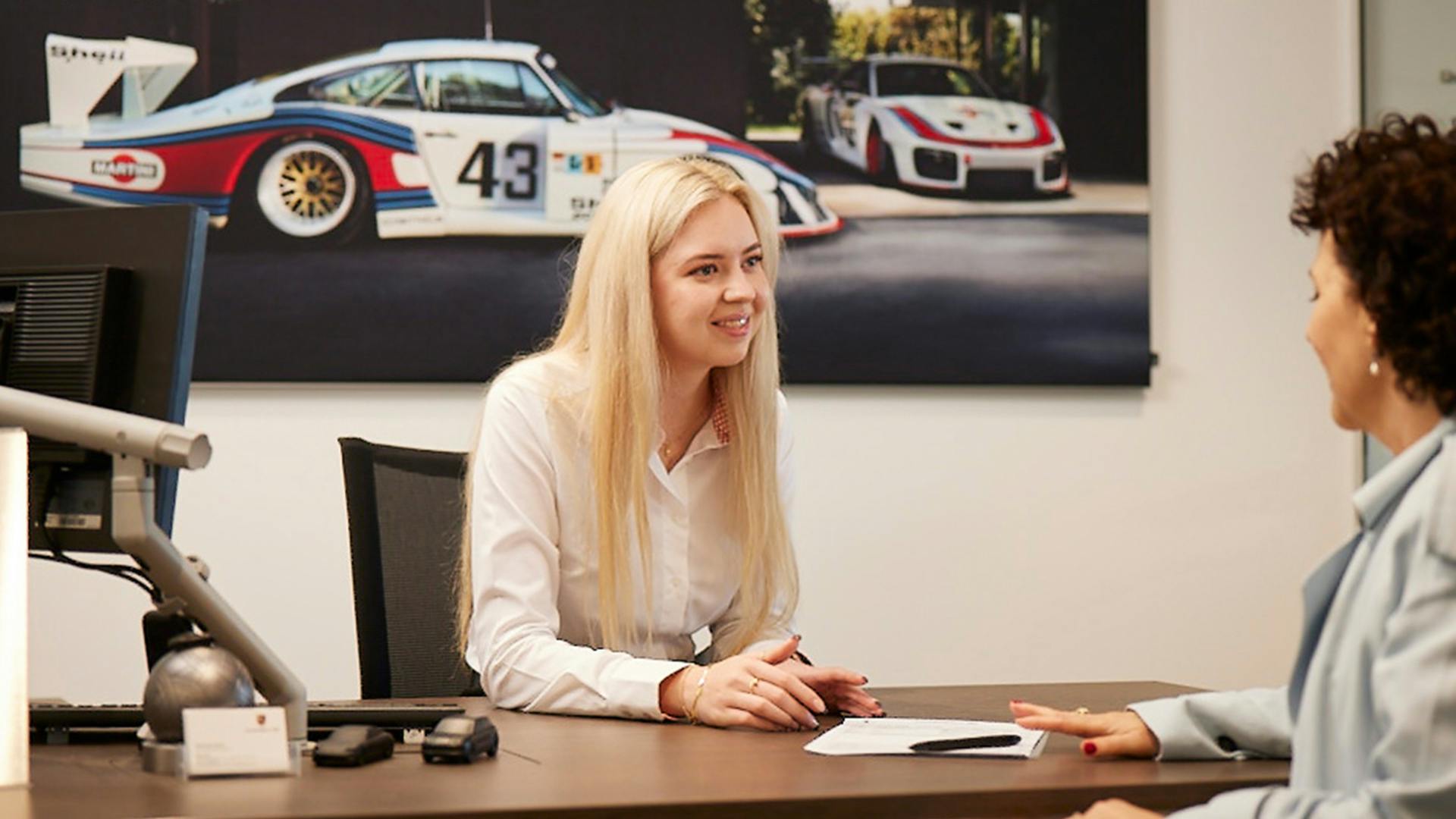 Porsche Service Consultant speaking with customer in an office.