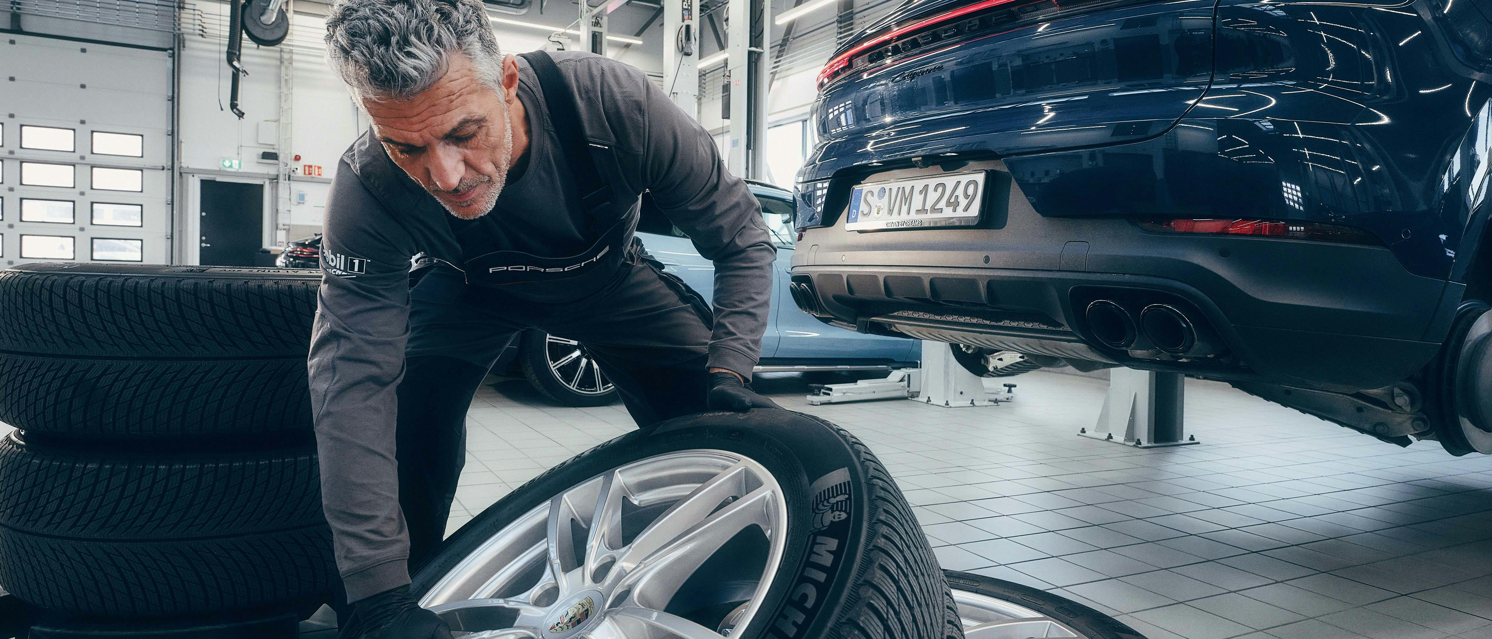 Een man in een Porsche werkplaats die banden aan het vervangen is