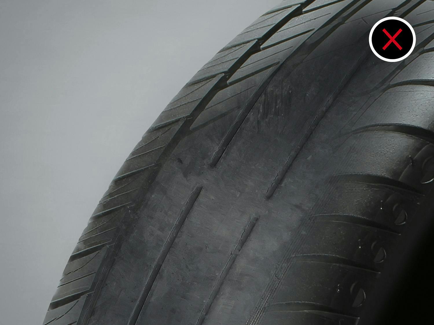 Tire with worn-out tread and an X mark, indicating poor condition.