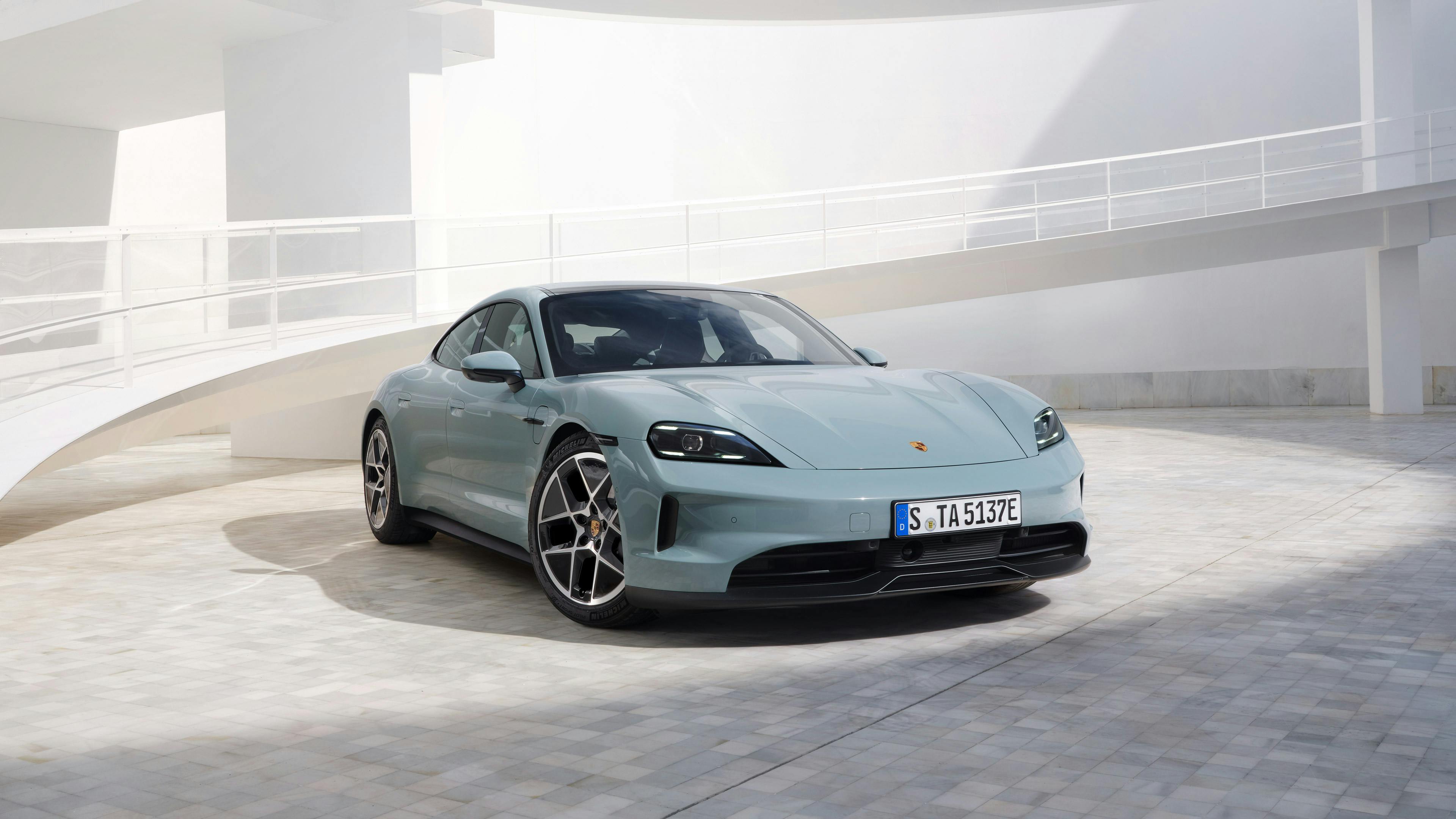 La Porsche Taycan bleue garée dans un espace moderne, avec une rampe blanche en arrière-plan.