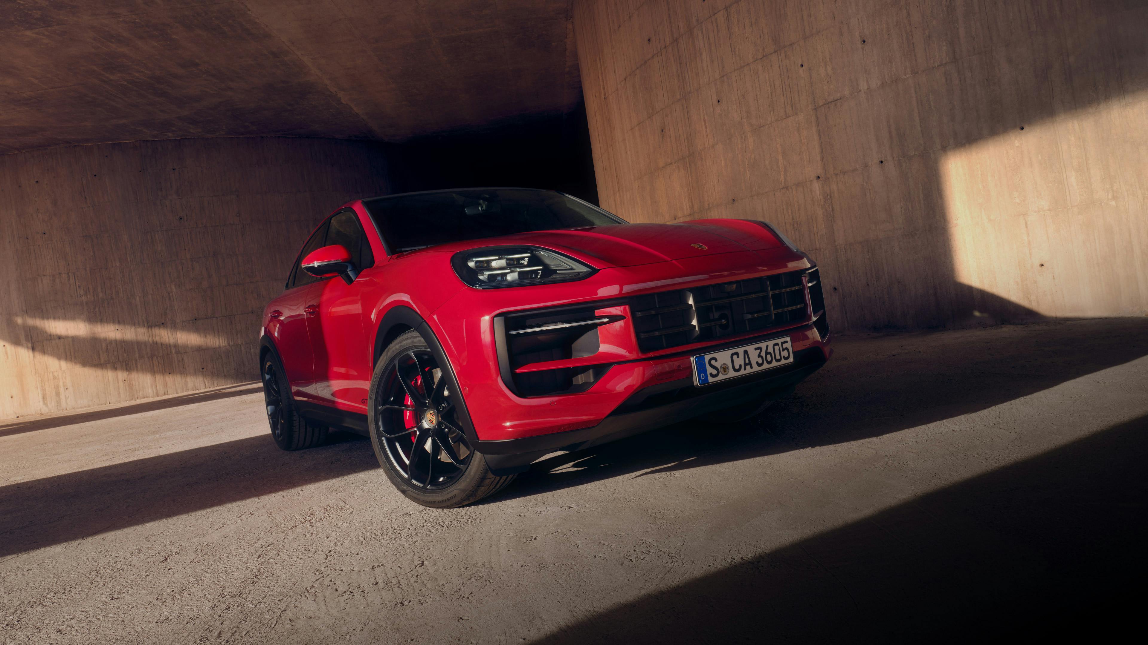 Una Porsche Cayenne blu attraversa una strada cittadina.