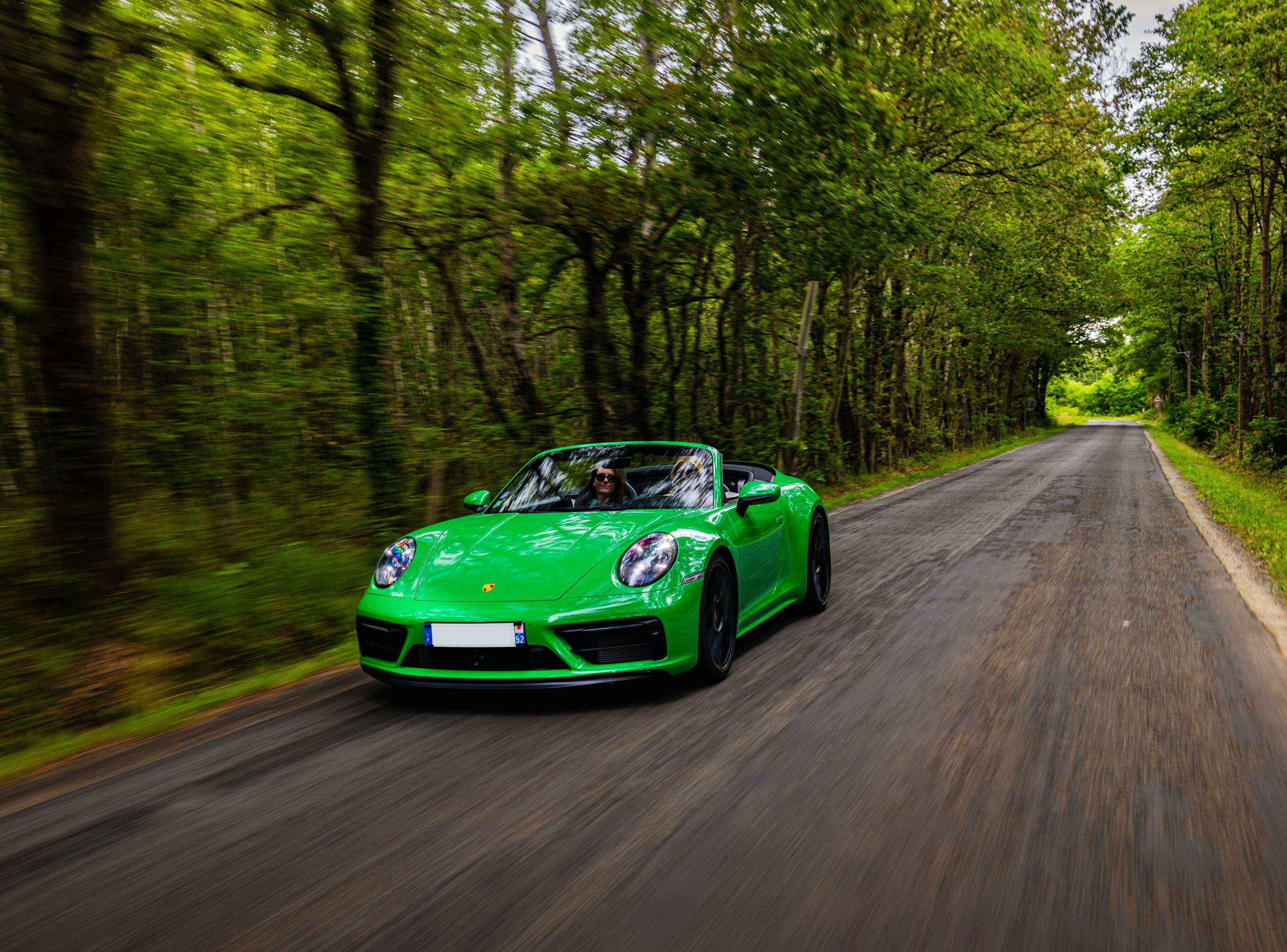 Un couple d’amies au volant d’une 911 Coupé Cabriolet verte dans les bois.