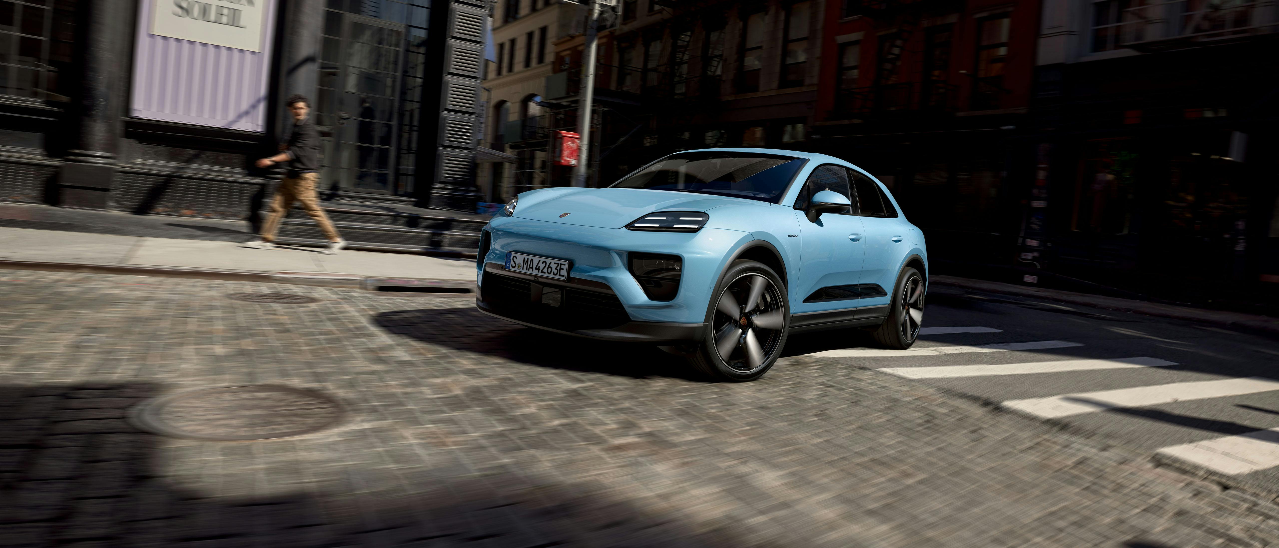 Een elektrische Porsche Macan rijdt door een straat in een stad.