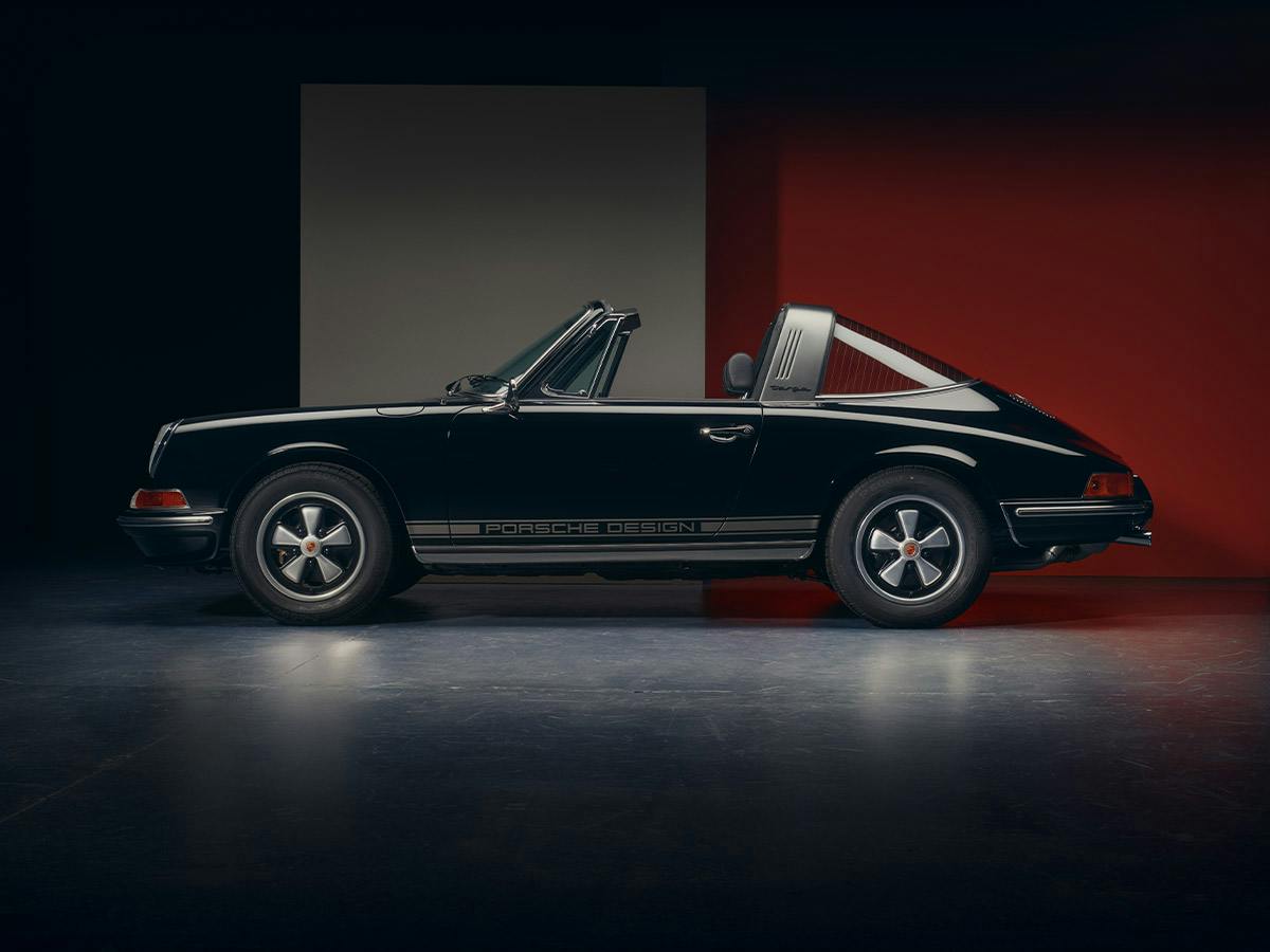 A 911 Targa S2.4 F-Modell with Cabriolet open coloured in Black with side stripes in Platinum and integrated Porsche Design lettering from the left side.