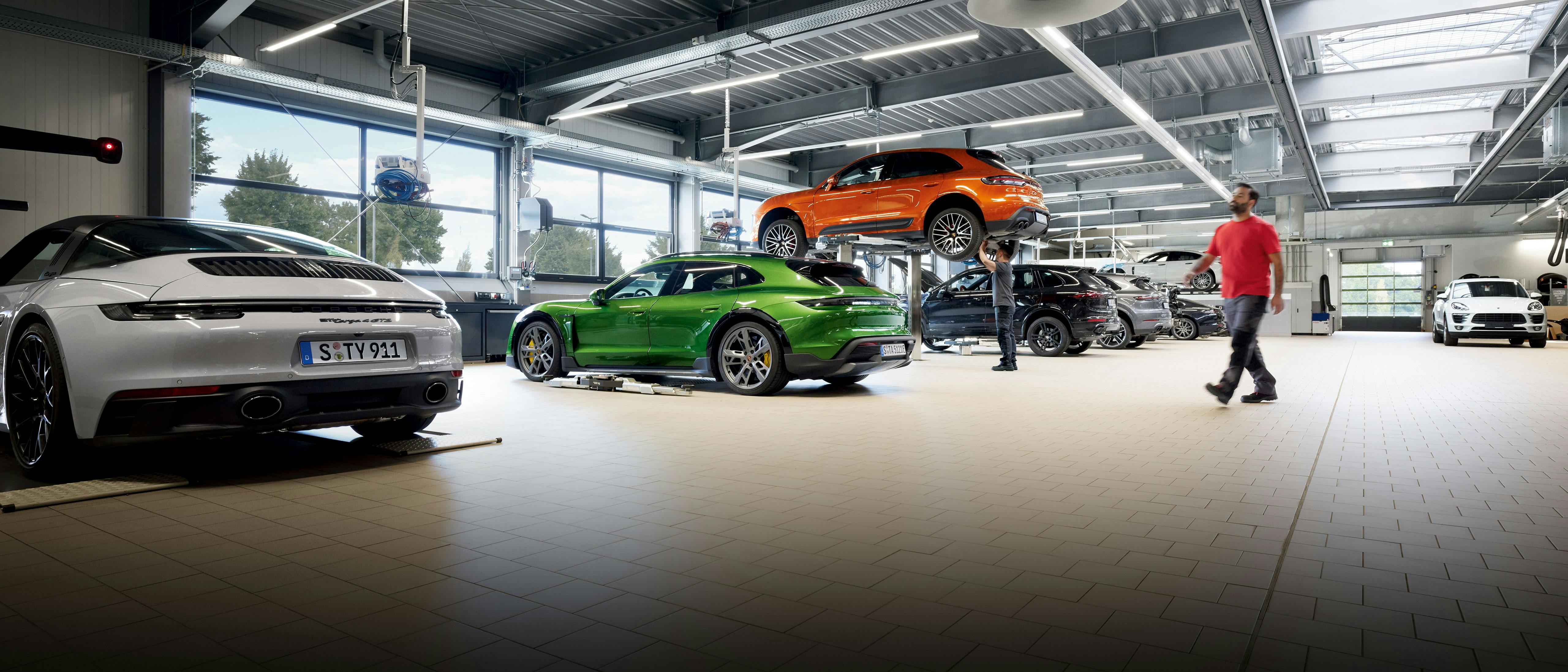 Interno di un’officina Porsche con 911, Taycan, Macan e Cayenne in riparazione