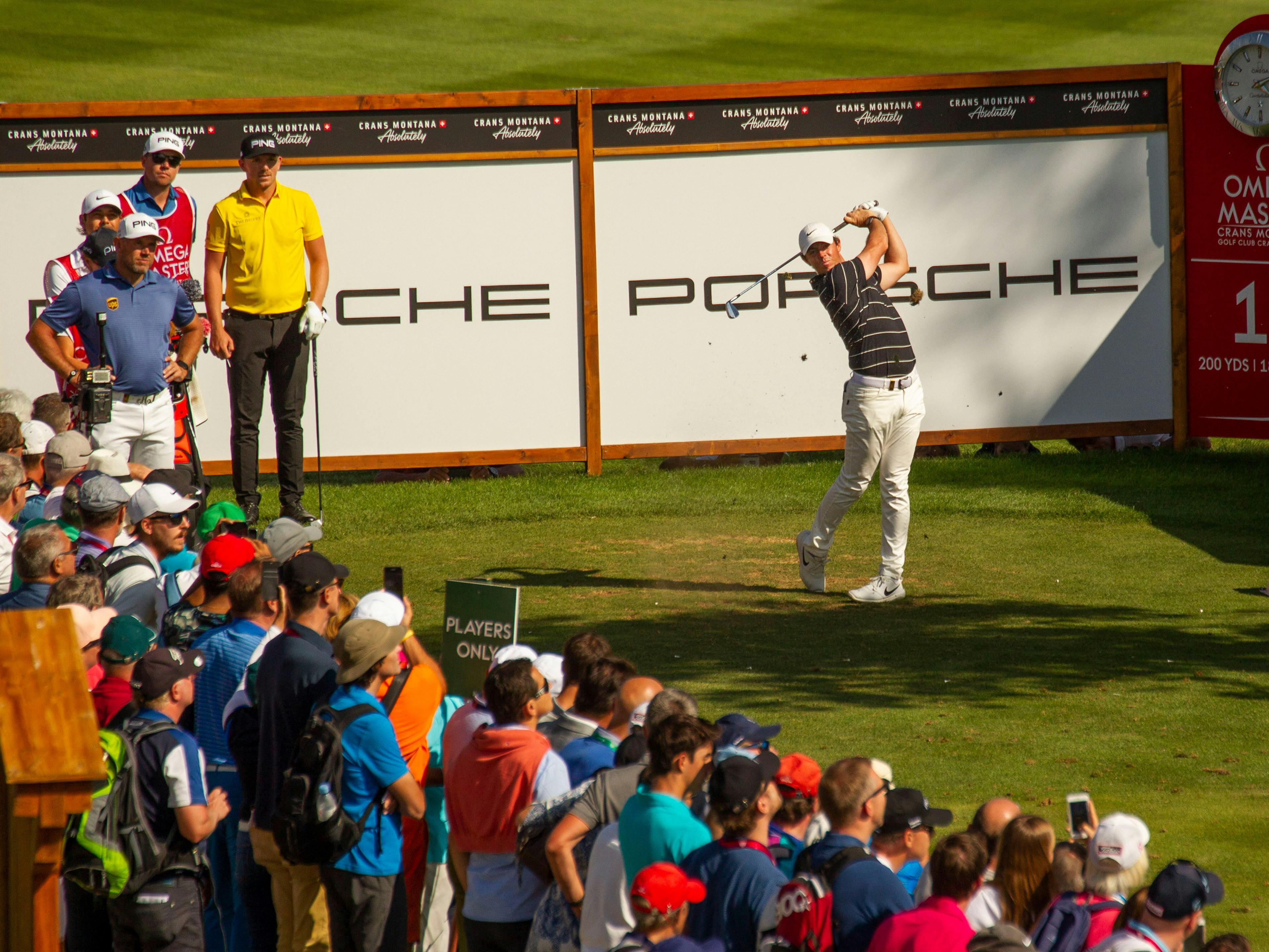 Ein Golfspieler beim Abschlag auf Bahn 11 der Omega European Masters vor Publikum