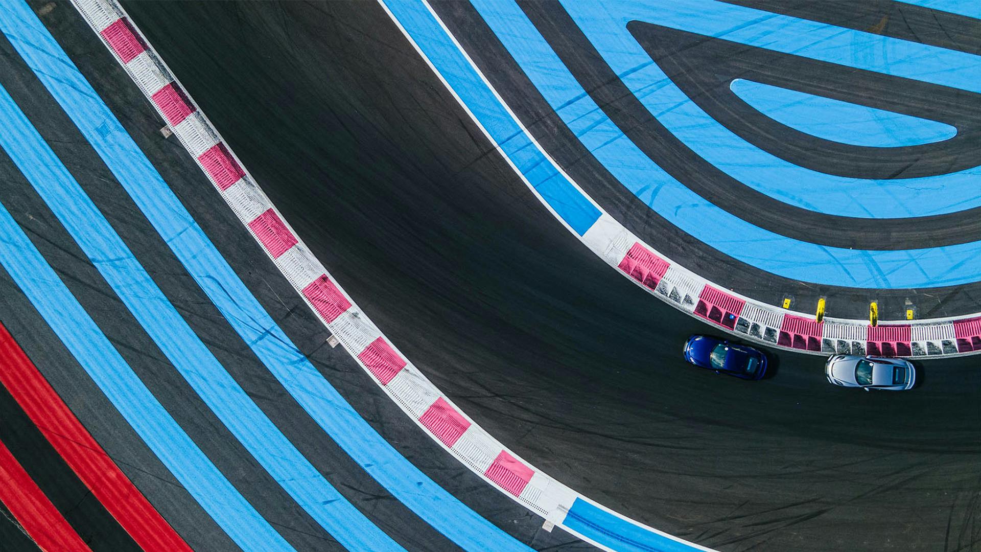 Two Porsches turn a corner with coloured run-off zones on the Circuit Paul Ricard.