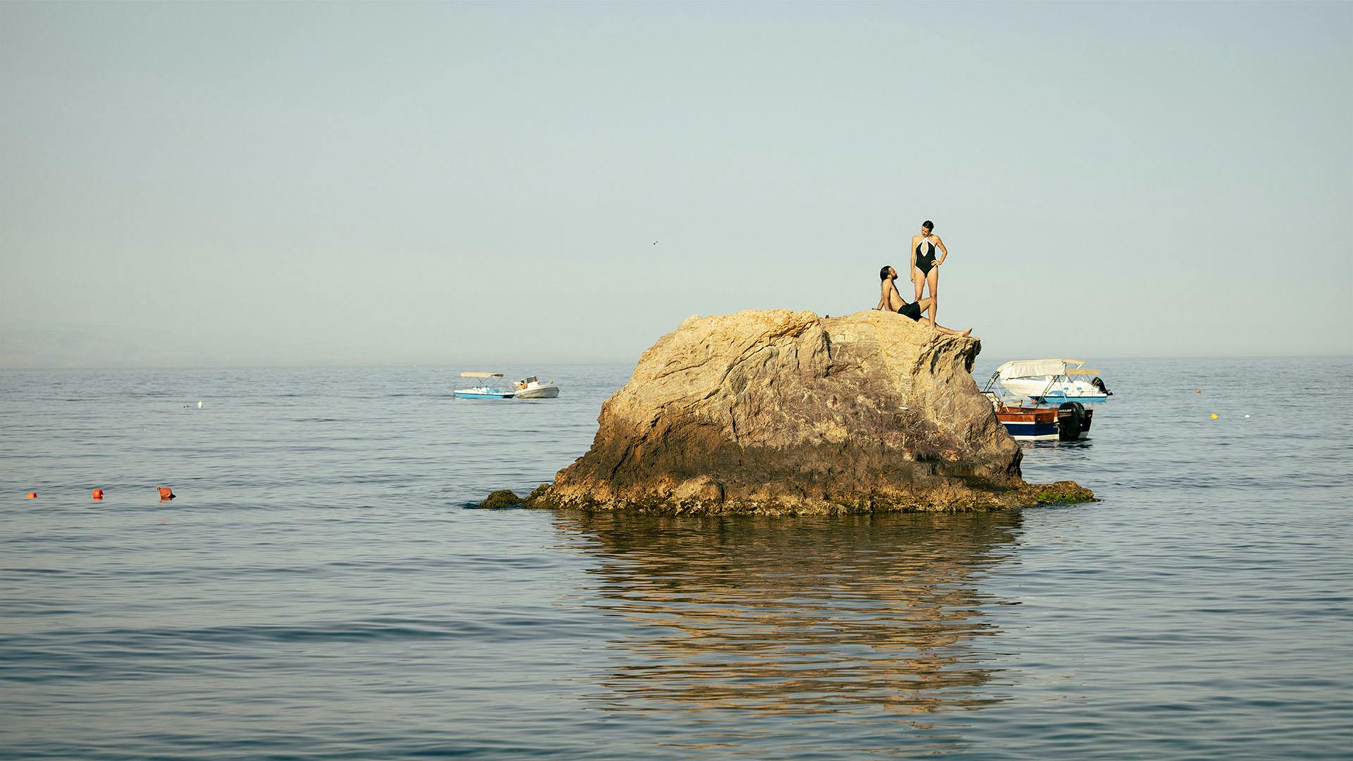 Holidaymakers on a rock, surrounded by the endless expanse of water.