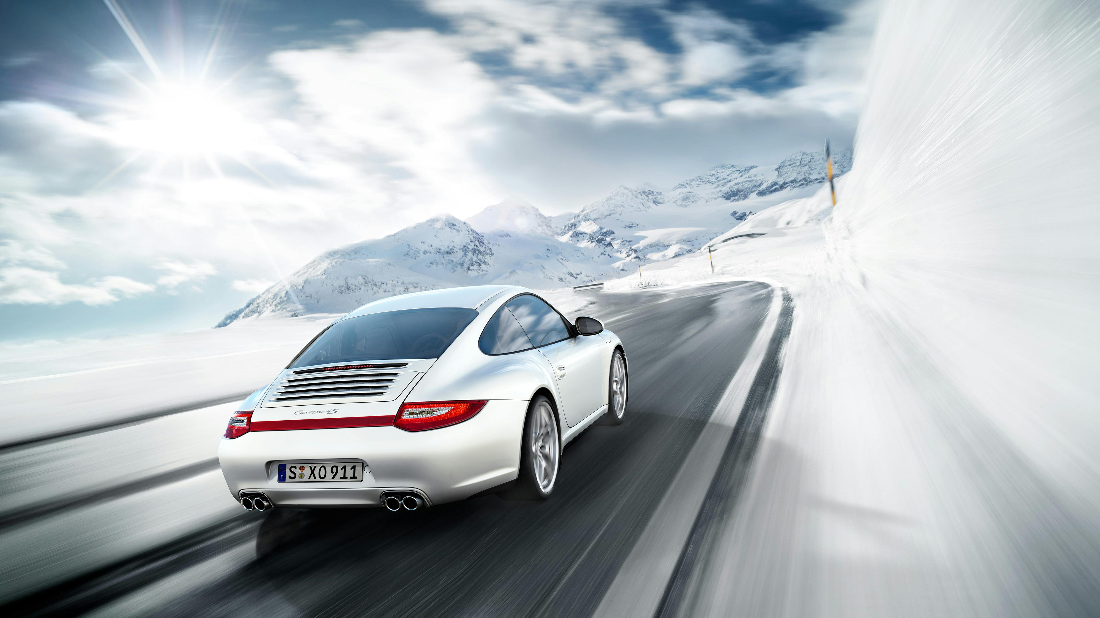Driving silver 911 Carrera 4S of the type 997 in a wintry mountain landscape.