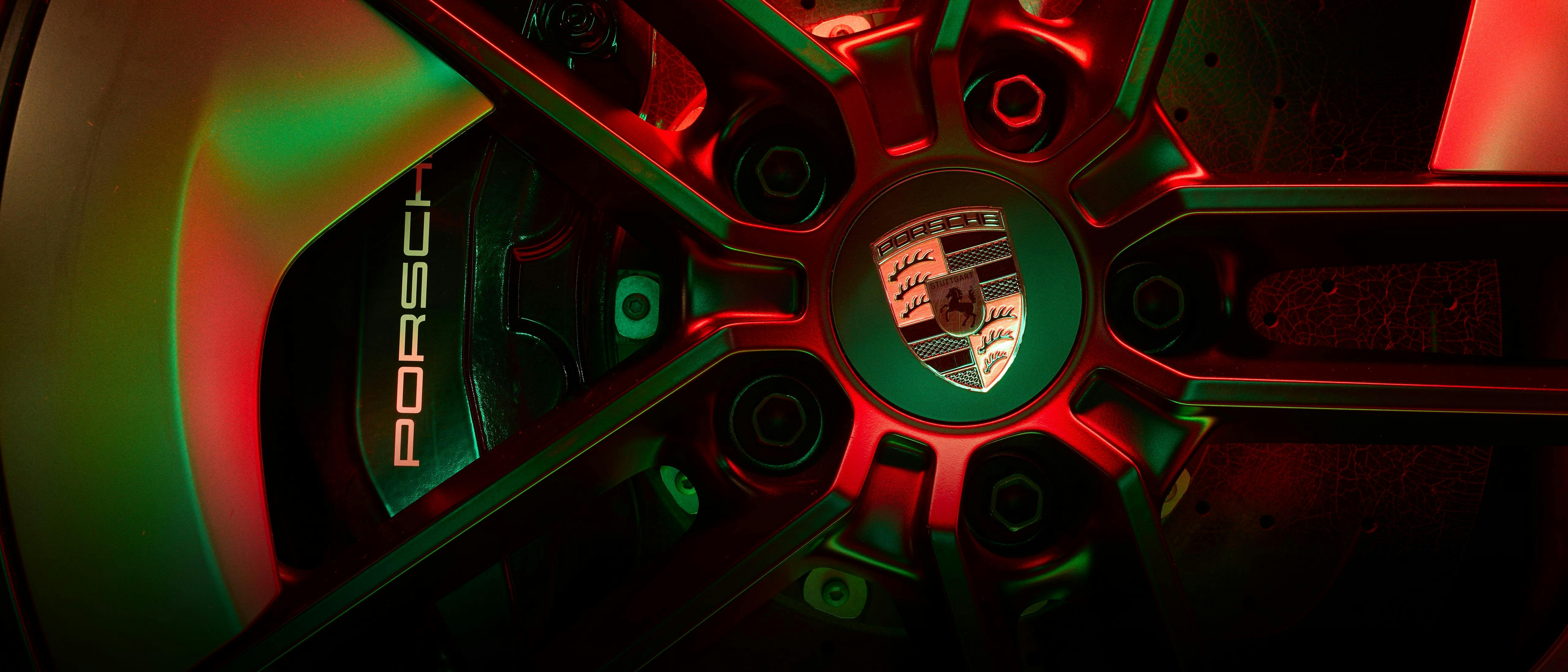 A rim of the Taycan Turbo is illuminated with red-green light.