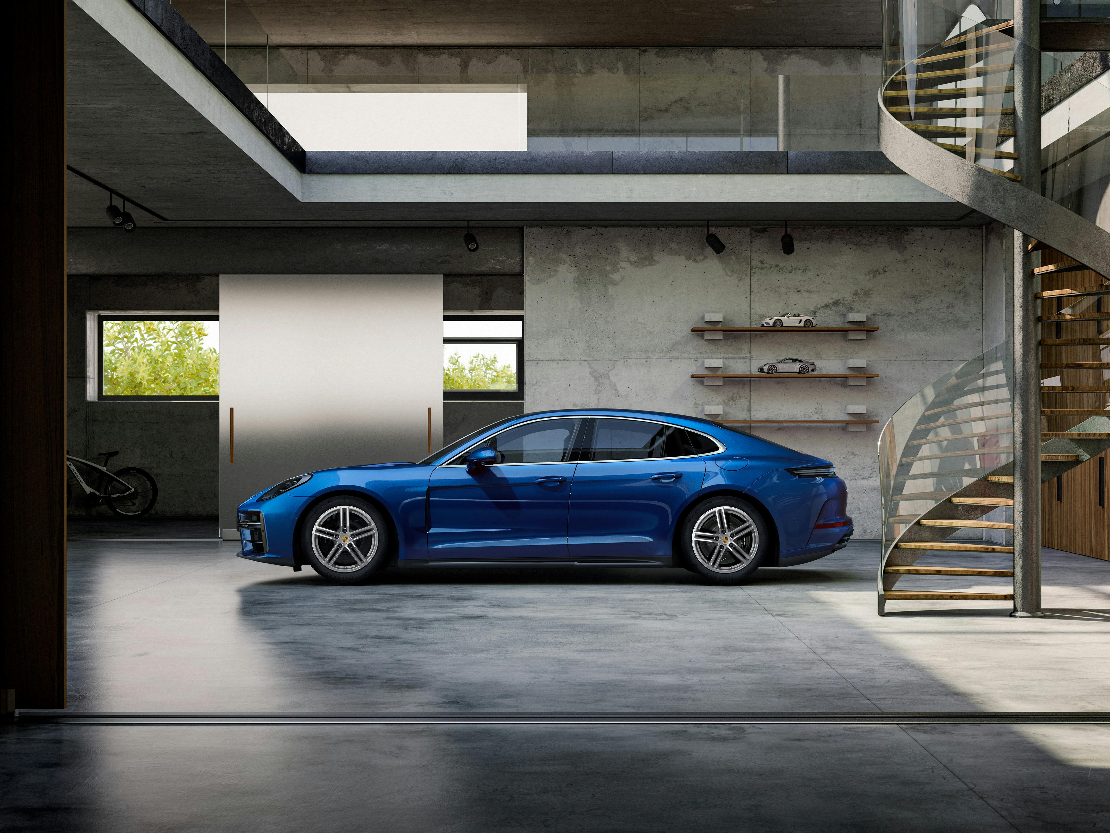 Ein blauer Porsche Panamera ist in einer Garage geparkt, mit einer modernen Treppe und Dekor im Hintergrund.