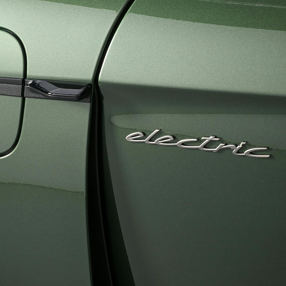 Close-up of a green Porsche electric car, showing the charging port cover with an embossed charging symbol on the left and the word "electric" in sleek chrome lettering on the right.