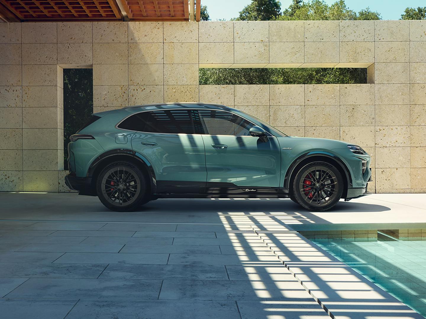 The Cayenne Turbo Electric SUV parked in a vibrant, modern environment, with a pool nearby.