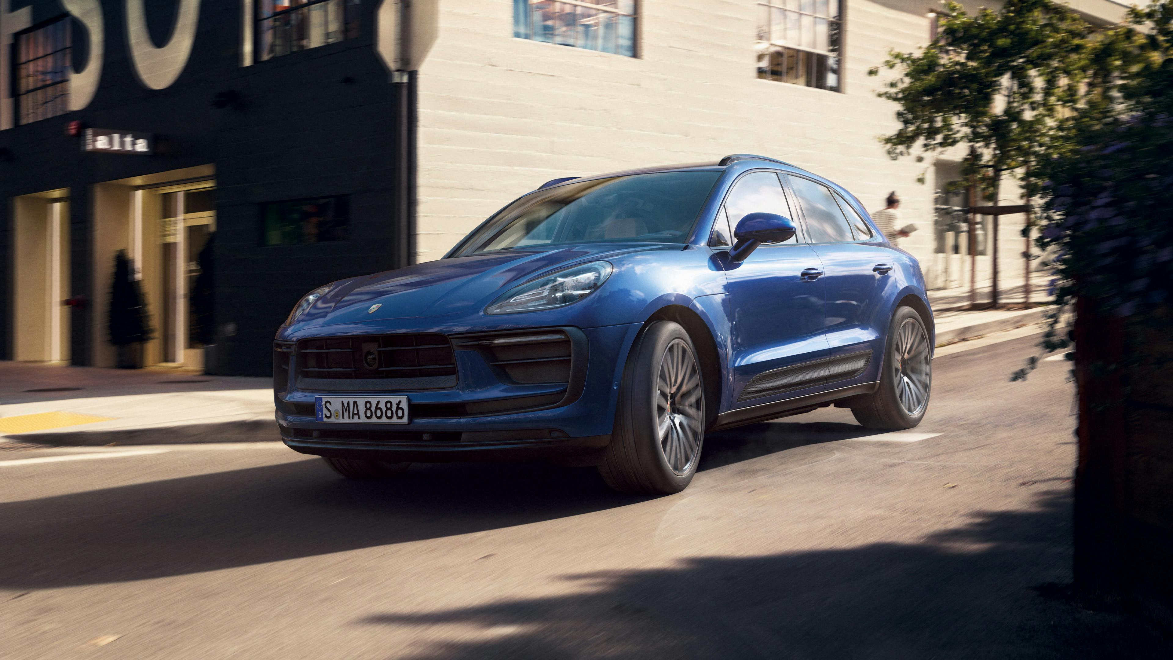 Une Porsche Macan bleue roulant dans une rue de la ville.