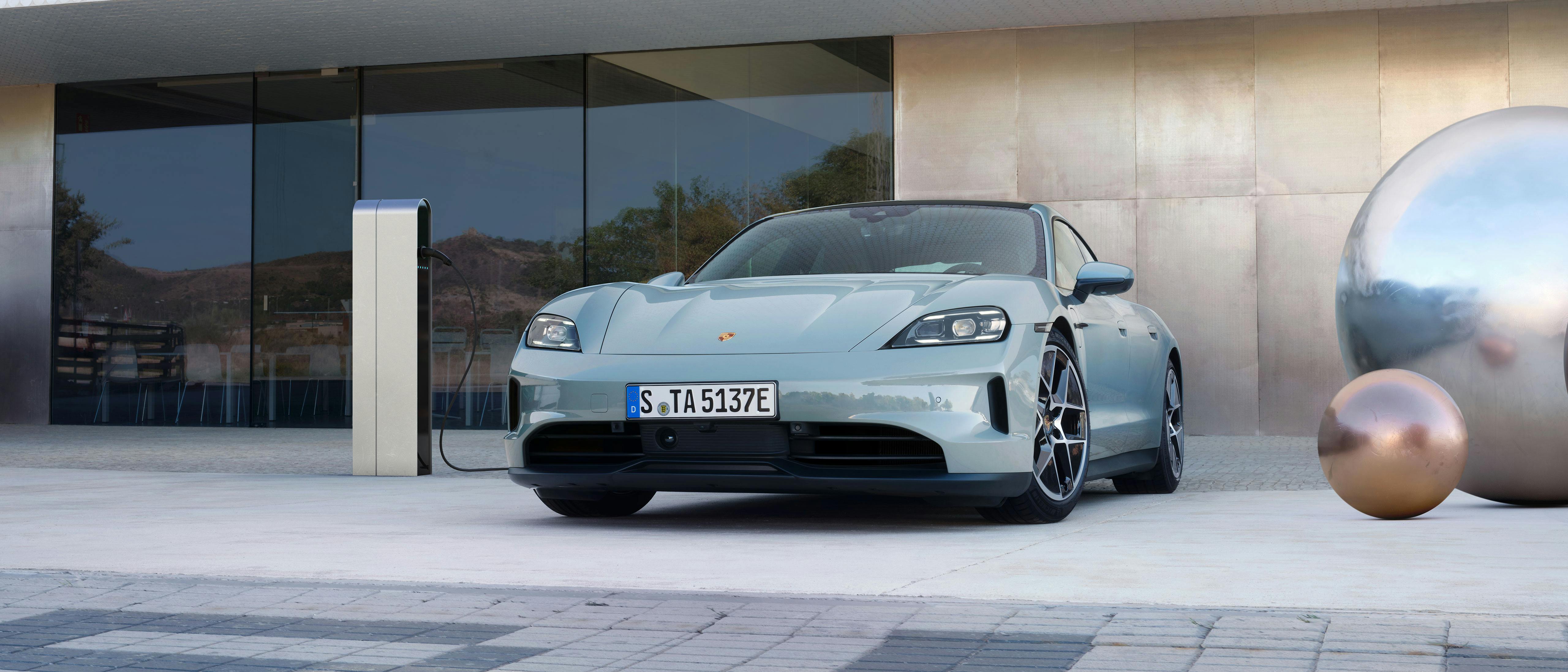 Un Porsche Taycan bleu clair en branché sur une station de recharge.
