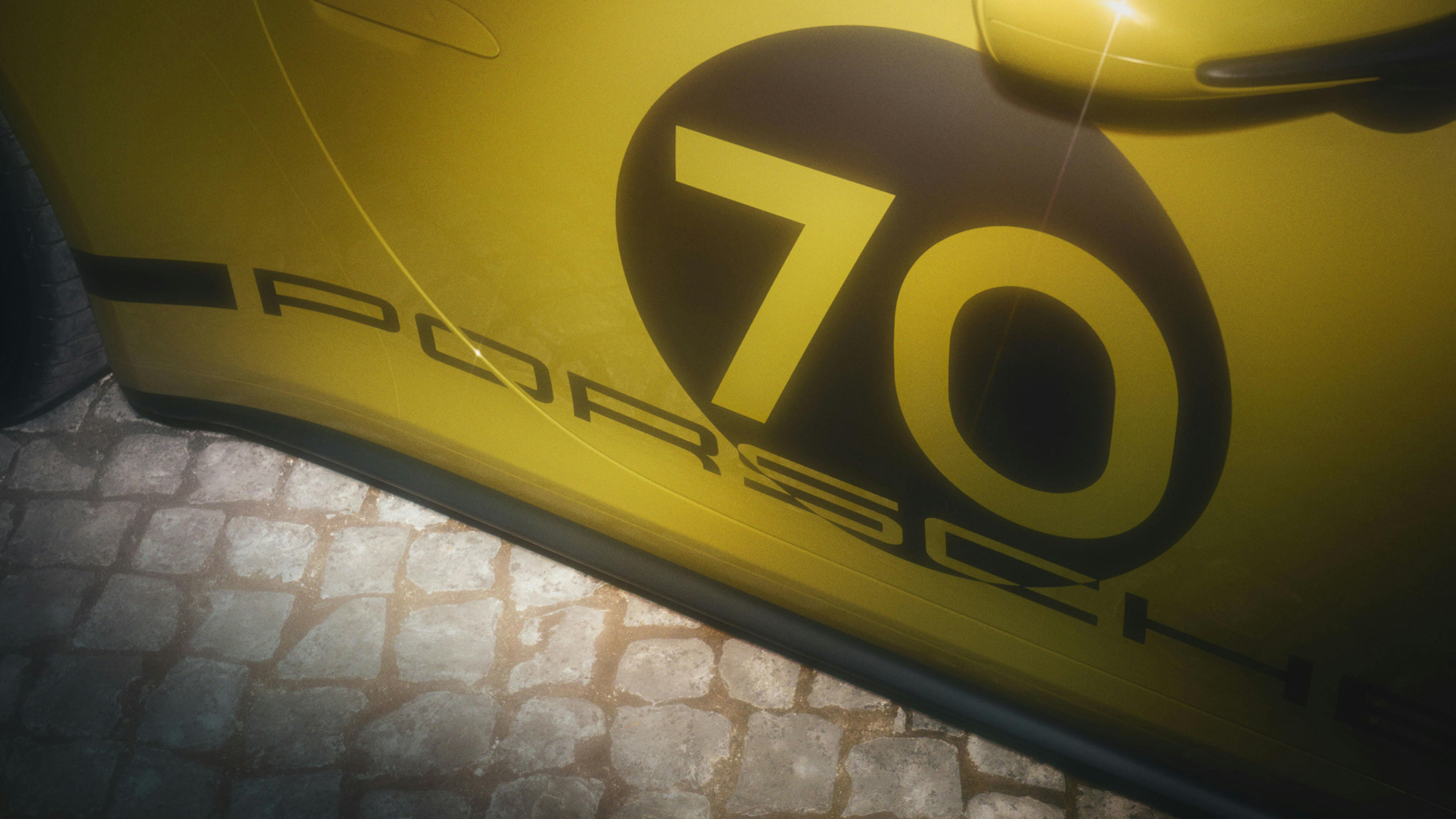 Detalle de la carrocería de un Porsche 911 70 Spirit amarillo, mostrando el diseño gráfico "70" y la palabra "Porsche".