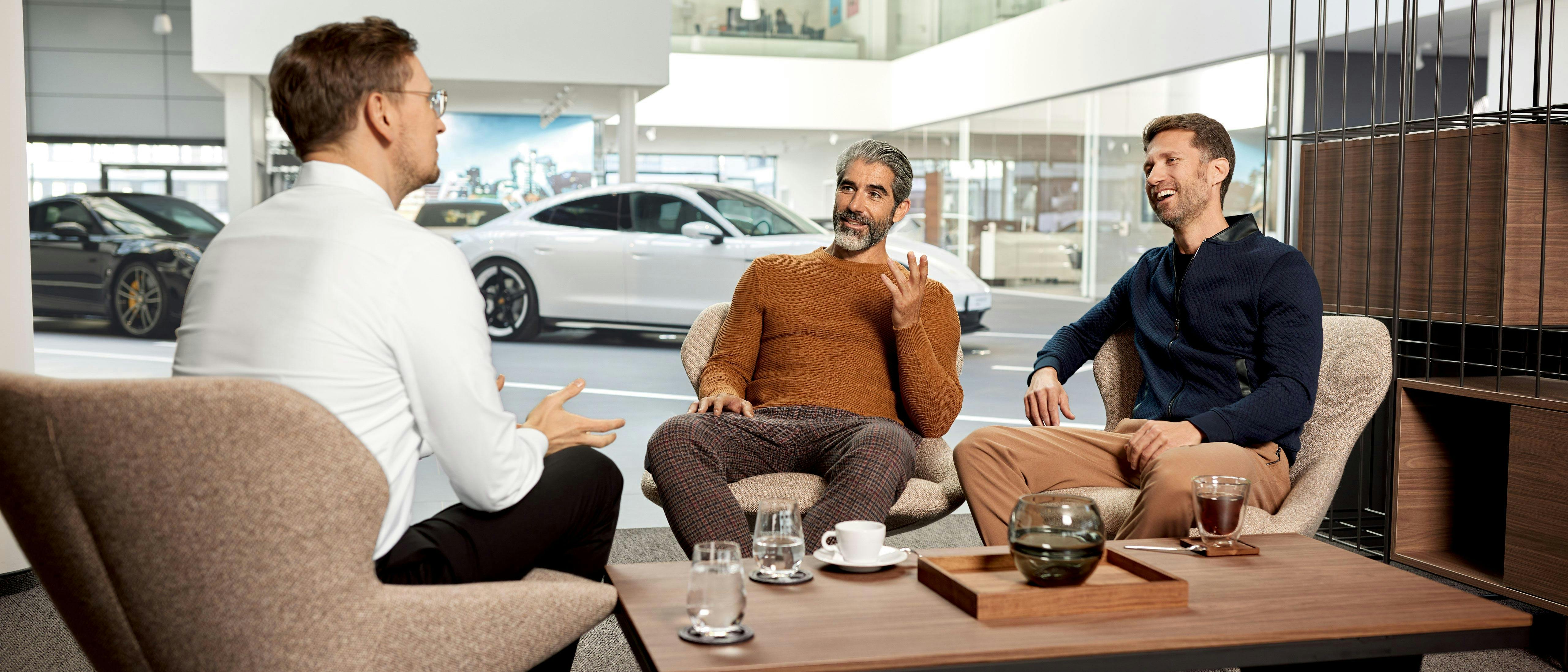 Two customers with Porsche employee sitting by a coffee table
